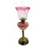A late Victorian brass oil lamp with cranberry and clear frosted glass shade, etched decorated