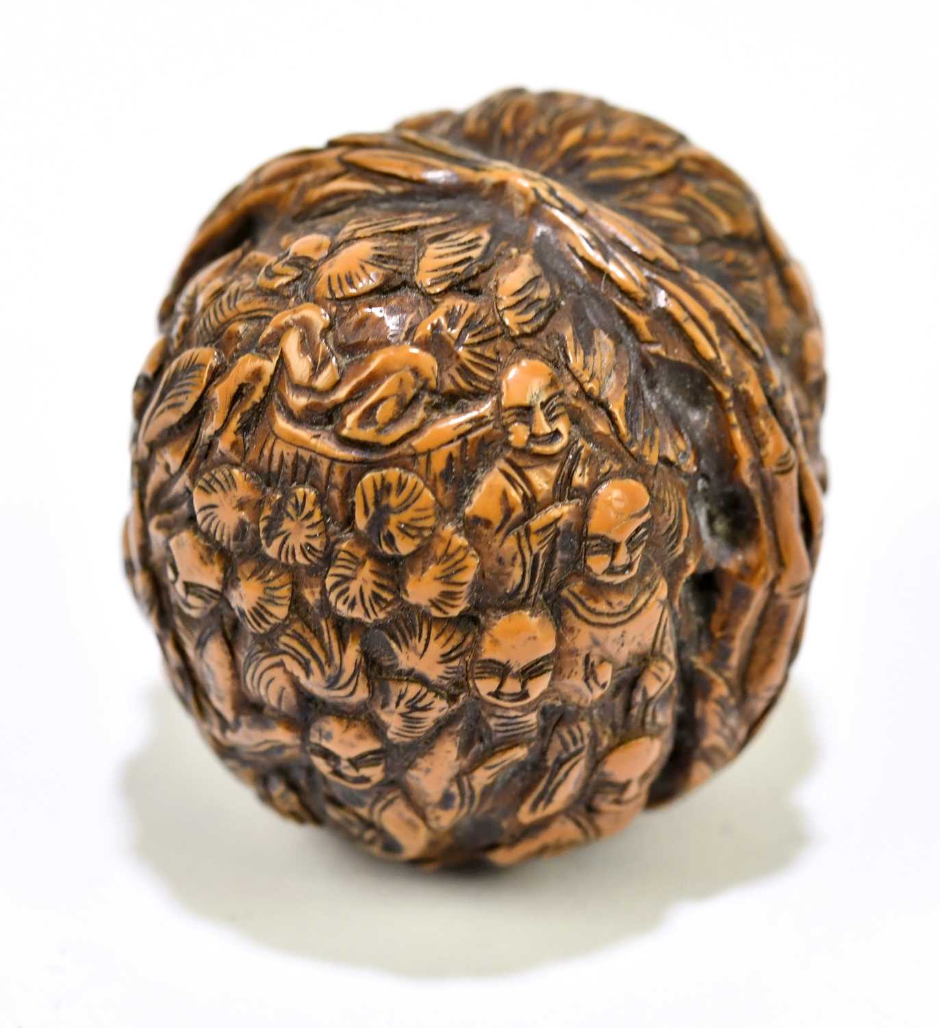 A Japanese carved walnut, decorated with figures within floral detail, height 3cm.