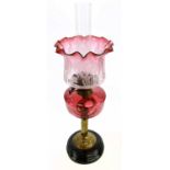 A late Victorian brass oil lamp, with cranberry and clear glass shade with etched floral