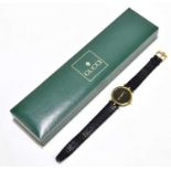 GUCCI; a gentleman's gold plated wristwatch, with plain black dial, with leather strap and buckle,