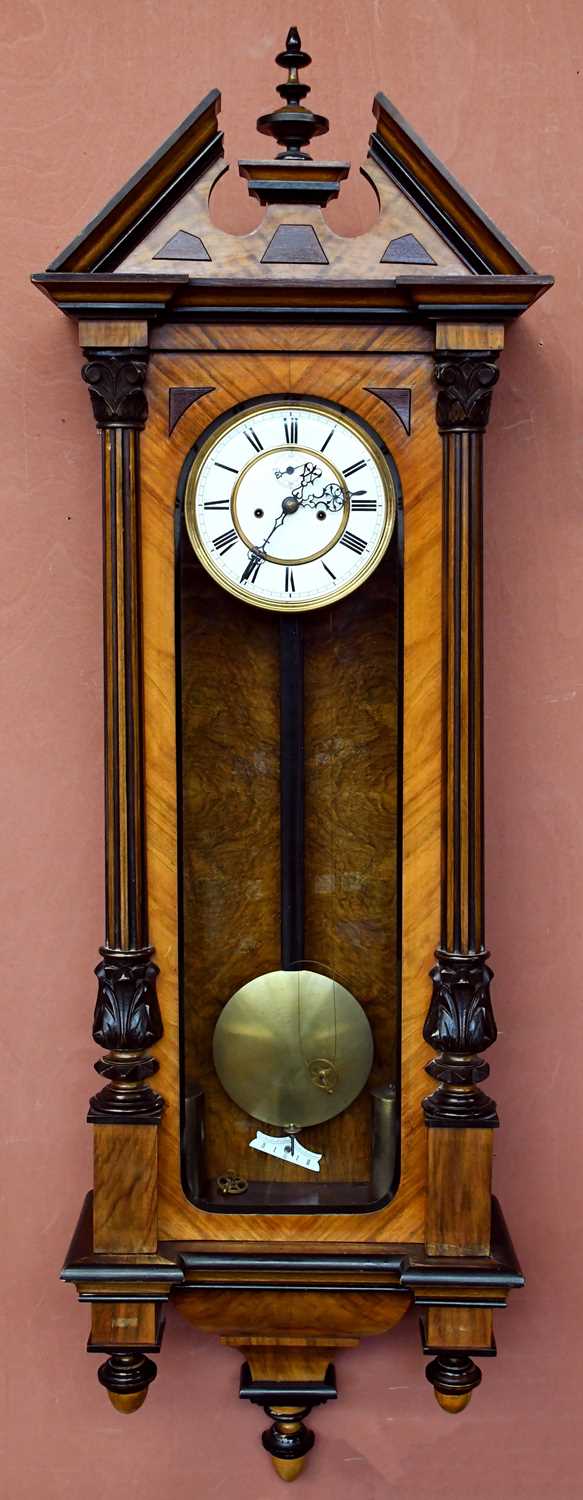 A 19th century walnut and stained pine Vienna wall clock with turned pediment above the circular