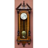 A 19th century walnut and stained pine Vienna wall clock with turned pediment above the circular