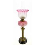 A Victorian oil lamp, with cranberry and clear frosted glass shade, decorated wtih sunflowers