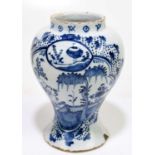 An 18th century English Delft drug jar, decorated with a cartouche of peonies and a fence, height