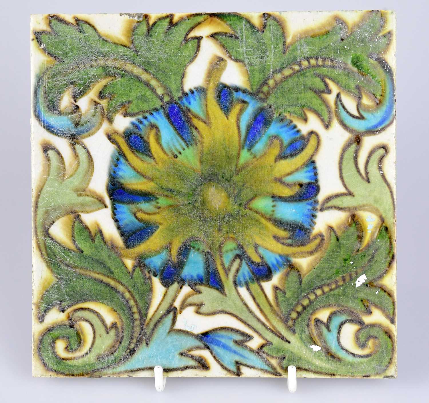 ATTRIBUTED TO MAW & CO; an Art Pottery tile painted with floral decoration, in shades of green,