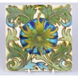 ATTRIBUTED TO MAW & CO; an Art Pottery tile painted with floral decoration, in shades of green,
