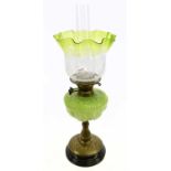 An Art Nouveau oil lamp with green and clear glass shade etched with floral detail above the moulded