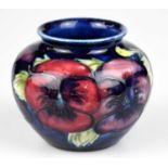 WALTER MOORCROFT; a squat vase in the 'Pansy' pattern on a blue ground, impressed marks to the