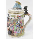 An ornate Capodimonte tankard, the hinged lid with brass eagle thumb piece and surmounted with a