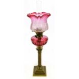 A Victorian brass oil lamp, with frosted cranberry glass shade, etched with floral detail above