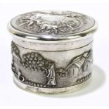 An Indian white metal lidded trinket box, decorated with village scenes.