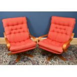 A pair of circa 1970s revolving easy chairs upholstered with red coloured button back and seated