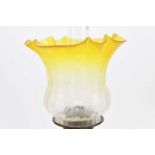 An early 20th century oil lamp with yellow and clear frosted glass shade above the moulded yellow