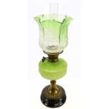 An early 20th century oil lamp with green and clear shade, with frosted floral decoration on a