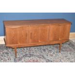 A mid-century teak sideboard with two short drawers over two cupboard doors, next to fall-front