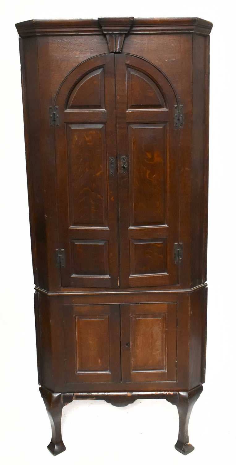 A Georgian oak freestanding corner cupboard with moulded cornice above a pair of arch shaped