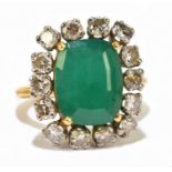 An unmarked yellow metal emerald and diamond cluster ring, the central rounded rectangular emerald