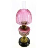 A late 19th/early 20th century oil lamp, with dome shaped cranberry coloured shade, with etched