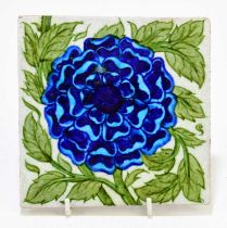WILLIAM DE MORGAN TILE; a glazed earthenware tile decorated with a blue flower, oval mark verso,