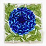 WILLIAM DE MORGAN TILE; a glazed earthenware tile decorated with a blue flower, oval mark verso,