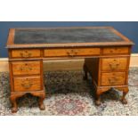 An Edwardian oak desk, with leather inset top above an arrangement of nine drawers, on cabriole legs