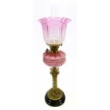 A Victorian oil lamp, cranberry and frosted glass shade with etched floral decoration on a