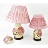 MOORCROFT; a graduated pair of lamps and a squat vase decorated in the 'Pink Hibiscus' pattern,