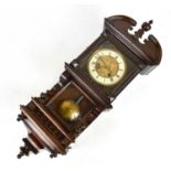 An early 20th century German stained wall clock with carved detail surrounding the dial bearing