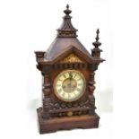 An early 20th century stained pine German mantel clock, the circular dial set with Roman numerals,