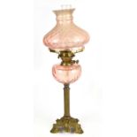 An early 20th century brass oil lamp with pink shade, height 66cm.