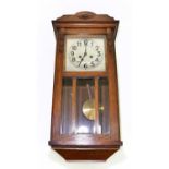 A 1930s oak wall clock, the dial set with Arabic numerals, approx 78cm.