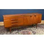 A mid century teak sideboard, with an arrangement of four drawers and two panelled cupboard doors,