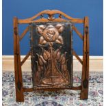 An Arts and Crafts style embossed copper and carved oak fire screen, the central copper panel