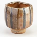 JEFF OESTREICH (born 1947); a faceted wood fired stoneware yunomi covered in pitted shino and iron