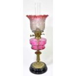 A Victorian oil lamp, the cranberry and clear glass shade with pinched rim, decorated with floral