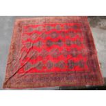 A large hand knotted carpet with geometric decoration and symbols, on a predominantly red ground,