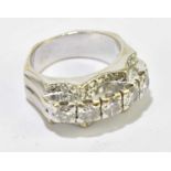 A white metal diamond ring with five raised brilliant cut stones flanked by smaller stones, size J