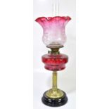 A Victorian oil lamp, the cranberry and clear glass shade with wavy rim, unusually decorated with