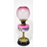 A Victorian oil lamp, the globular cranberry and milk glass shade with etched floral decoration