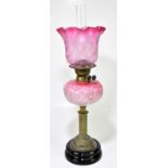 A Victorian oil lamp, the cranberry and clear glass shade with etched swags, above the moulded