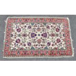 An Eastern style carpet with floral decoration on a cream, salmon pink and green ground, 146 x