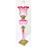 A Victorian oil lamp, with cranberry and clear glass shade with wavy rim above etched floral