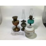 A group of three oil lamps to include a brass example, a blue glass example, etc.