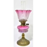 A late 19th century oil lamp, the cranberry and clear glass shade, with wavy rim, with etched floral