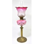 A late 19th century oil lamp with cranberry and clear glass shade with frosted decoration of