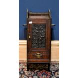An early 20th century carved oak smoker's cabinet with a panelled door, with tooled leather panel