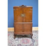 A 1950s burr walnut veneered cocktail cabinet, the twin panelled doors enclosing mirrored back and