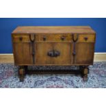 An early 20th century carved oak Art Deco sideboard with three drawers above four panelled