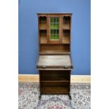 A late 19th/early 20th century oak roll top bookcase, the upper section with stained leaded glazed