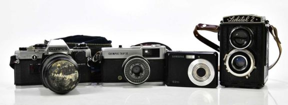 A group of four cameras, including Olympus OM10 with manual adapter and a 28270 lens, an Olympus